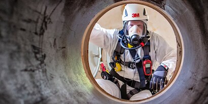 Een werknemer die een stofmasker en helm van 3M draagt
