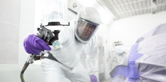 Spuiter die een deel van een auto spuit met het 3M performance spuitpistool
