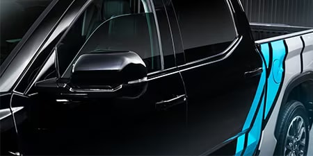 Details van een accentwrap in felblauw en wit op een zwarte pick-up.
