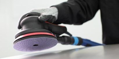Technicus die een beschadigd autopaneel schuurt
