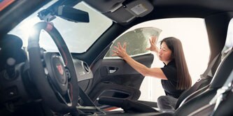 Vrouw die raamfolie op een auto aanbrengt
