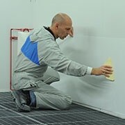 Man die het dirt trap beschermingsmateriaal op een wand aanbrengt met een spreider