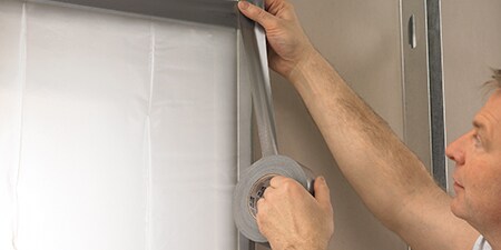 Een professional brengt 3M Ducttape en reparatietape aan op een muur
