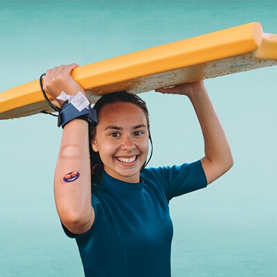 Afbeelding van een meisje dat een surfplank boven haar hoofd draagt
