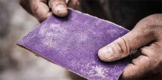 Professionele schilder gebruikt Cubritron™ II industriële schuurmiddelen voor het schuren.
