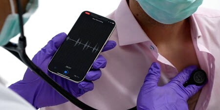 Behandelaar met Littmann digitalestethoscoop, kijkt naar live gegevens in de mobiele app
