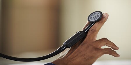 Close-up van Littmann CORE digitale stethoscoop liggend op de vingers van een persoon
