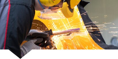 Technicus die een metalen carrosseriedeel snijdt.
