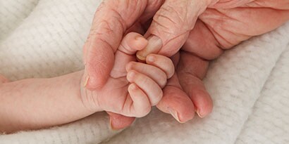 Persoon die de vingertjes van een baby vasthoudt
