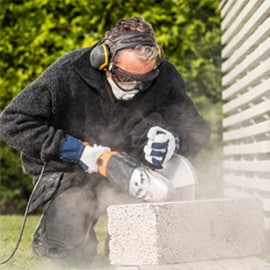 Professioneel schuren van een betonblok. Hij is volledig uitgerust met PBM veiligheidsproducten.