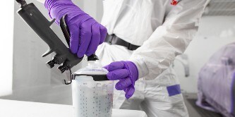 Spuiter die een spuitkop op een beker met lak zet

