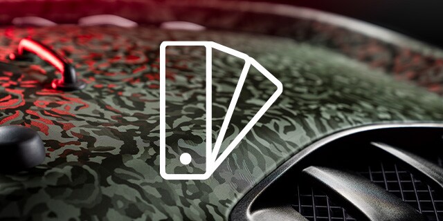 Detailopname van wrapfolie op motorkap met camouflagepatroon en met staalpictogram
