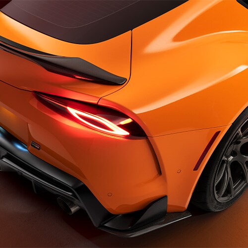 Detail van oranje wrapfolie de achterpassagierszijde van een sportwagen