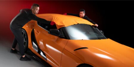 oranje autowrap die wordt aangebracht door twee installateurs
