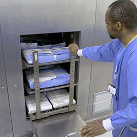 Een medewerker van de sterilisatieafdeling duwt de instrumententrolley in de sterilisator