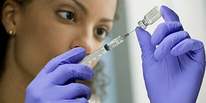 Vrouw die een injectiespuit en flacon gebruikt
