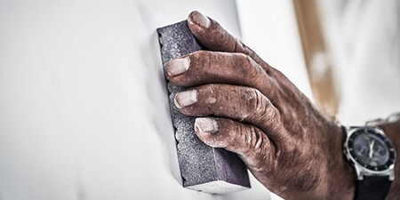 Een professionele decorateur schuurt een oppervlak met 3M Geavanceerde schuurmaterialen
