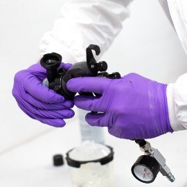 Handen met paarse handschoenen die een spuitkop van een 3M Performance Spuitpistool instellen