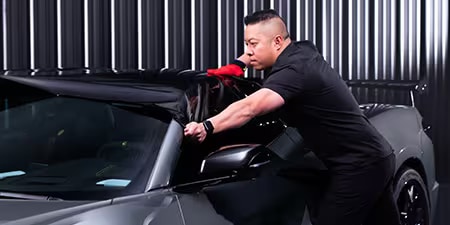 Wrap-installateur die folie op het dak van een auto aanbrengt.
