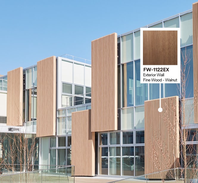 Buitenkant van gebouw met glazen en houten gevel met productaanduiding van notenhouten DINOC-exterieurfolie.