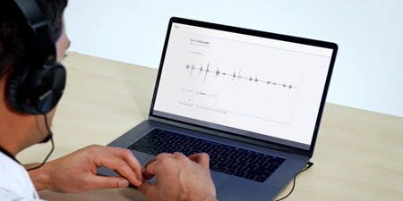 Behandelaar met een laptop kijkt naar de live telehealth auscultatievideo op de laptop
