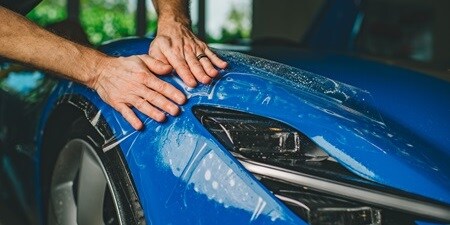 Persoon die verfbeschermingsfolie op een auto aanbrengt
