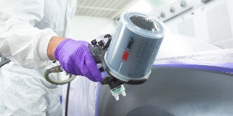 Spuiter die lak op een deel van een auto spuit met behulp van het 3M performance spuitpistool
