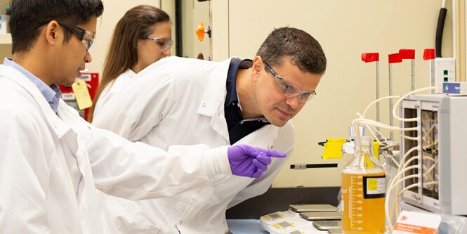 Wetenschappers in laboratoriumjassen inspecteren vloeistof

