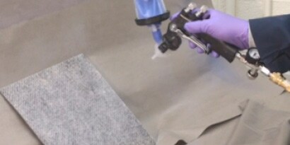 Vloeibare lijm die met applicator op textiel wordt gespoten
