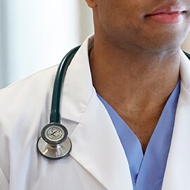 Littmann Stethoscoop op de juiste manier gedragen aan de buitenzijde van de kraag van een witte laboratoriumjas om te voorkomen dat de buizen de nek van de clinicus raken.