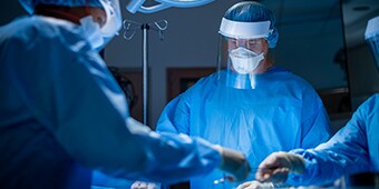 Drie chirurgen die chirurgische zorg verlenen
