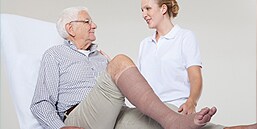 Zorgverlener in gesprek met patiënt waarbij compressietherapie wordt toegepast
