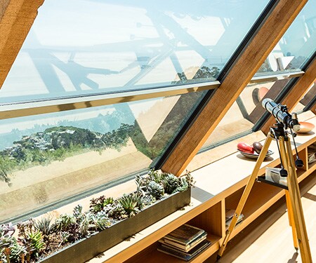 Interieur van huis met grote hoekramen die uitkijken op het strand
