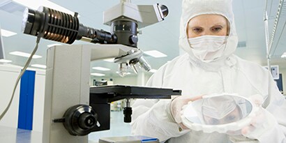 onderzoeker in laboratorium die een preparaat test onder een microscoop
