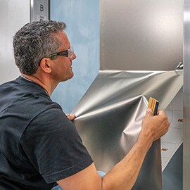 Man installeert zilver metallic 3M DINOC-afwerking op liftdeur