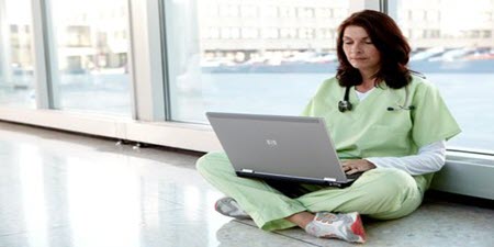 Clinicus zit op de grond en leest laptop
