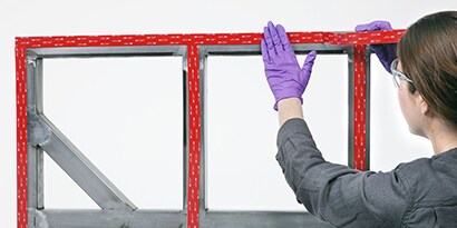 Technicus gebruikt industriële tape voor de bevestiging van panelen op een frame
